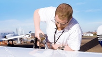 A technician pouring  Kerofluid® MIL-AL-41,  BASF'S fuel system icing inhibitor in a airplane